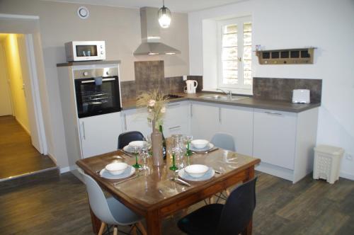 a kitchen with a wooden table with chairs and a dining room at La Cour Royale in Bayeux
