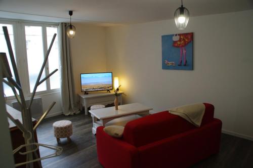 a living room with a red couch and a tv at La Cour Royale in Bayeux