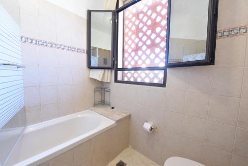 a bathroom with a tub and a toilet and a window at Flintstone Guest House בית ההארחה בן 11 החדרים אינו וילה פרטית אתם מזמינים רק חדרים לא את כל הוילה in Eilat