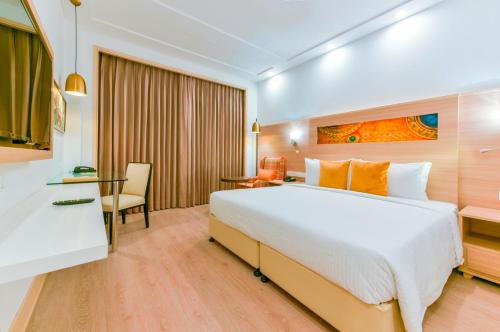 a hotel room with a large bed and a desk at Lemon Tree Hotel Jammu in Jammu