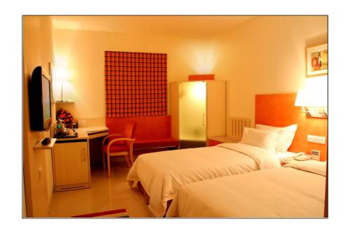 a hotel room with two beds and a desk at Aditya Hometel in Hyderabad