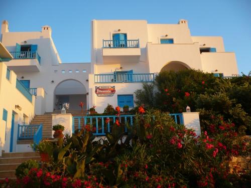 a group of white buildings with flowers in front of them at Hotel Filoxenia in Aegiali