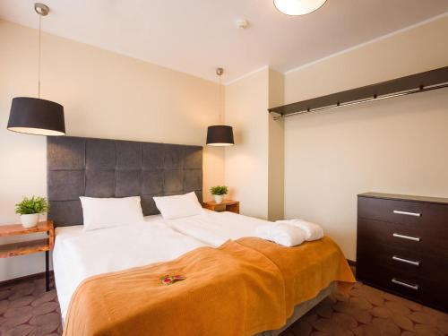 a bedroom with a large bed with an orange blanket at VacationClub - Sand Hotel Apartment 308 in Kołobrzeg