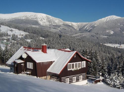 a barn in the snow with mountains in the background at Pension Skalicky in Pec pod Sněžkou