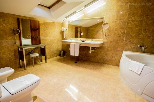 a bathroom with a tub and a sink and a toilet at Hotel Silvota in Lugo de Llanera