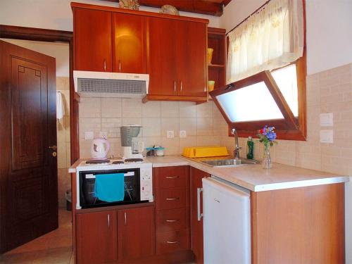 a small kitchen with wooden cabinets and a microwave at Christinas lofts in Ágios Matthaíos