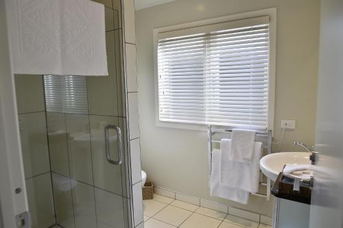 een badkamer met een glazen douche en een wastafel bij Bradleys Garden Bed and Breakfast in Taumarunui