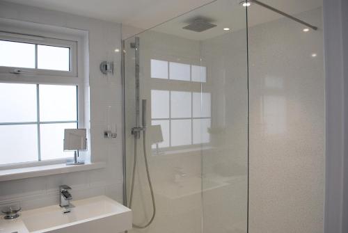 a bathroom with a glass shower and a sink at The Lodge, Polgooth in St Austell