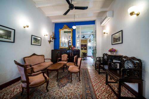 a living room with chairs and a table and a mirror at Nam Keng Hotel Penang in George Town