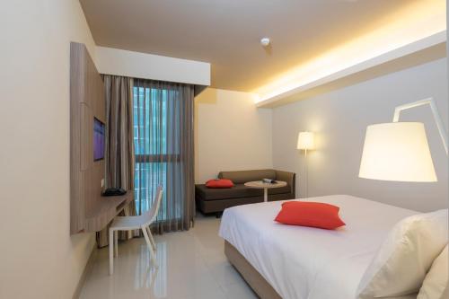 a hotel room with a bed with a red pillow on it at Travelodge Pattaya in Pattaya Central