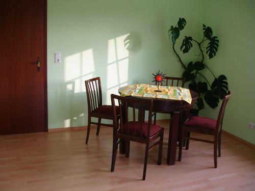 a dining room table with four chairs and a plant at Ferienwohnung Schob in Dyrotz