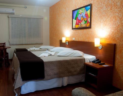 um quarto de hotel com uma cama grande e uma janela em Hotel Rafeli em Boituva
