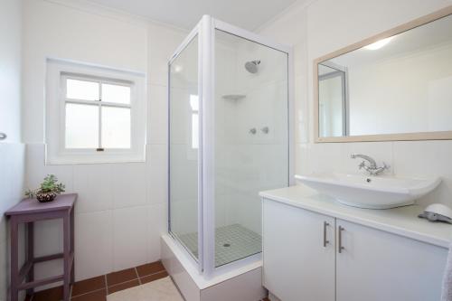 a white bathroom with a sink and a shower at Stone Chimney Cottage in Hermanus