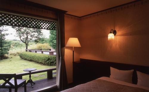 Schlafzimmer mit einem Fenster mit Blick auf den Hof in der Unterkunft Canari in Nasu