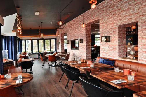 un restaurant avec des tables et des chaises en bois et un mur en briques dans l'établissement Boutique Hotel Herbergh Amsterdam Airport FREE PARKING, à Badhoevedorp