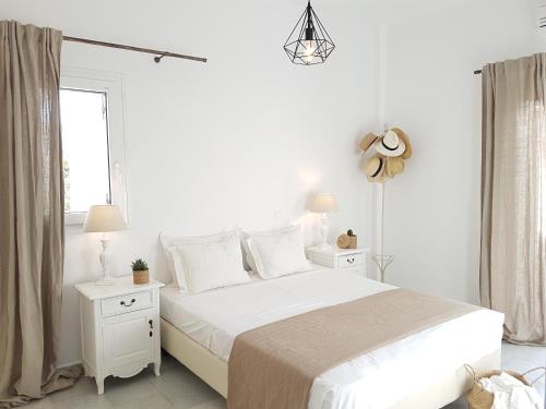 a white bedroom with a large bed with two night stands at Artemis Sunny Villa in Antiparos