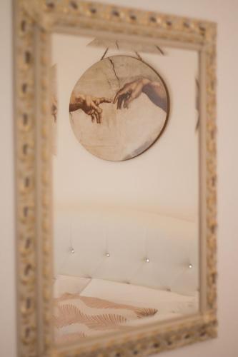 a mirror hanging on a wall with a painting at Palazzo Rattazzi in Monopoli