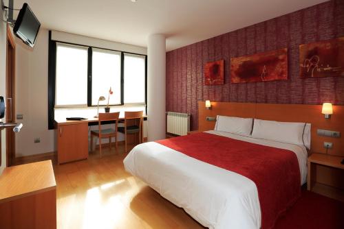 una camera d'albergo con un grande letto e una scrivania di Hotel Txarriduna a Elgoibar