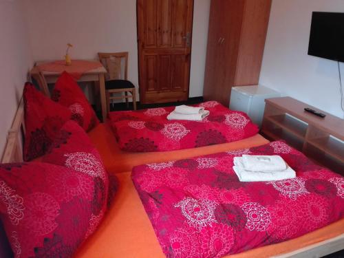 two beds in a room with red sheets and towels at Penzion U Hyklů in Veřovice