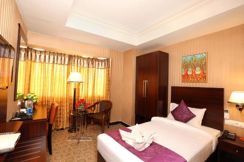 a hotel room with a bed and a desk at Cochin Legacy in Cochin