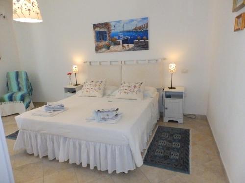 een slaapkamer met een groot wit bed en 2 tafels bij Sa Chessa B&B in Ploaghe