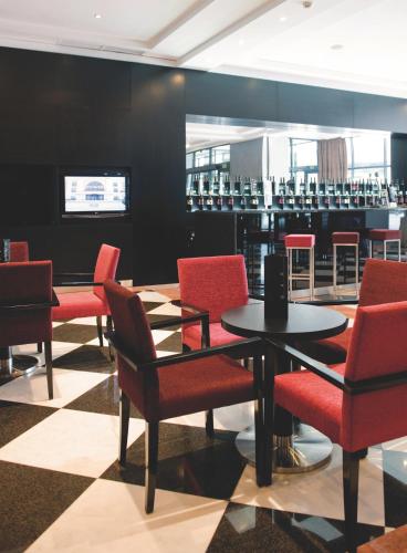 a restaurant with red chairs and a table andools at Vila Gale Porto - Centro in Porto