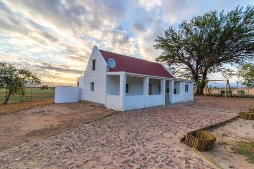 a small white building with a red roof at Volmoed Cottage in Oudtshoorn