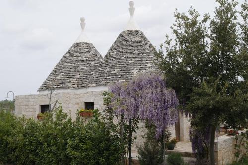 an old stone building with two towers with purple wisterisks at Vacanza In Puglia in Alberobello