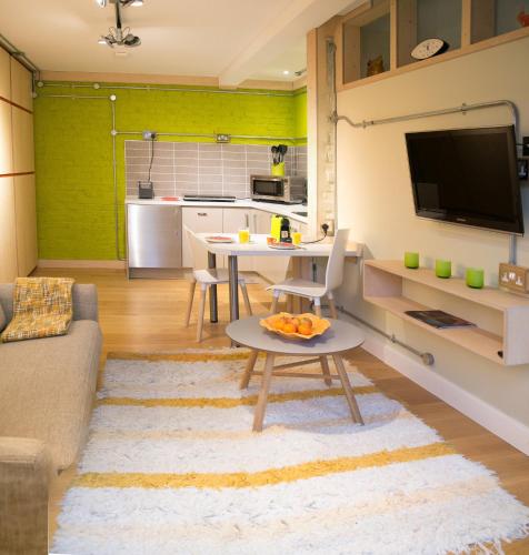 a living room with a table and a kitchen at Claron Lodge in West Wittering