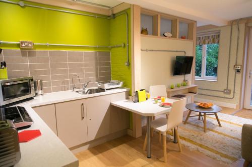 a kitchen with green walls and a table and chairs at Claron Lodge in West Wittering