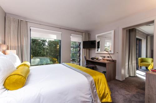 a hotel room with a bed and a desk and a window at Greenlands Hotel in Henley on Thames