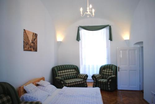 a room with two chairs and a bed and a window at Dobó Téri Apartman in Eger