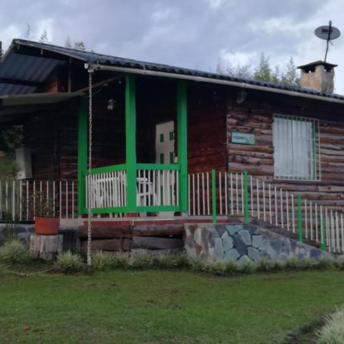 a log cabin with a green front porch at Hotel Campestre El Refugio de Balsora in Filandia