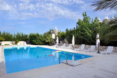 una piscina con sillas blancas y una piscina en Vacanza In Puglia, en Alberobello