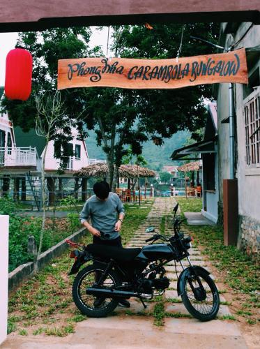 a man standing next to a motorcycle under a sign at Carambola Bungalow in Phong Nha