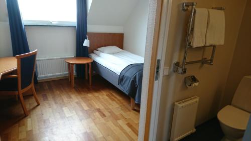 Cette petite chambre comprend un petit lit et une table. dans l'établissement Haga Värdshus, à Hillerstorp