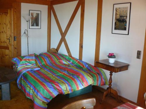 a bedroom with a colorful bed and a table at Ferienwohnung Naturhaus in Allensbach