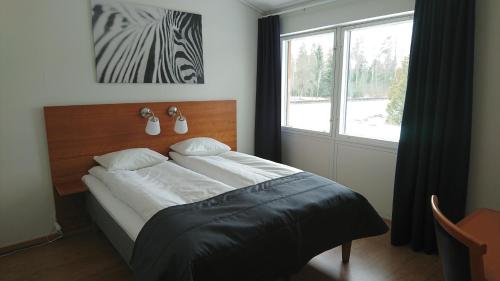 um quarto com uma cama e uma janela grande em Haga Värdshus em Hillerstorp