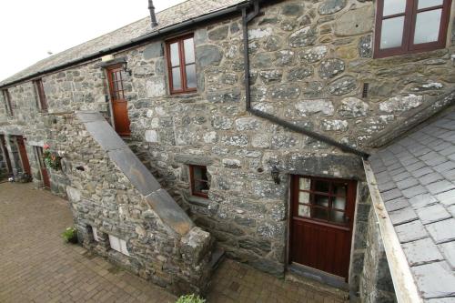 un antiguo edificio de piedra con una escalera. en Ystumgwern Luxury Barn Conversions, en Dyffryn