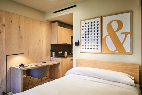 1 dormitorio con cama, escritorio y cocina en Numad Studios, en San Sebastián