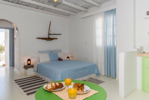 a white bedroom with a bed and a table with food on it at Thalassitra Village Hotel in Adamantas