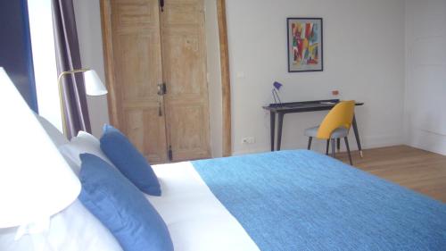a bedroom with a bed with blue pillows and a desk at Villa Marambat in Marambat