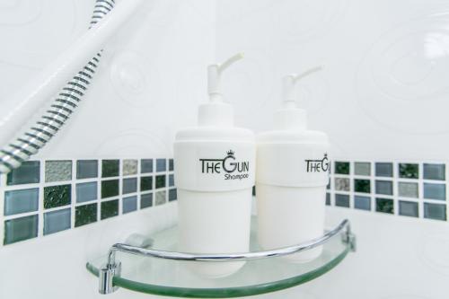 two white cups sitting on a glass table in a bathroom at The Gun Hotel in Surin