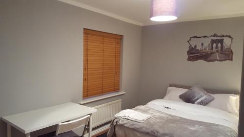 a bedroom with a bed and a desk and a window at Haus Serviced Living in Braintree