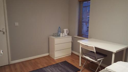 a bedroom with a desk and a dresser and a window at Haus Serviced Living in Braintree
