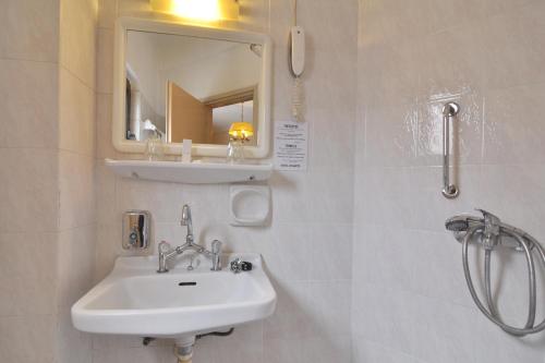 un bagno con lavandino, specchio e doccia di Hotel Atlantis a Città di Corfù