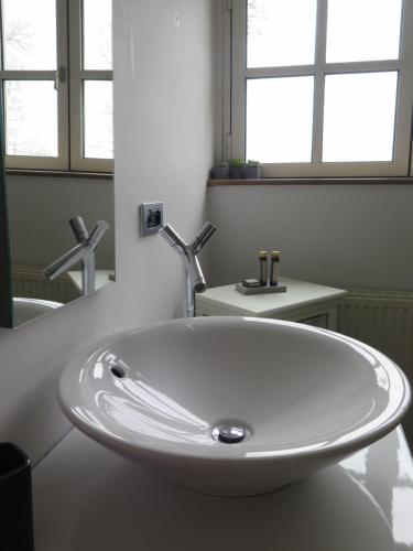 a white sink in a bathroom with two windows at B&B La Buissonniere in Xhoris