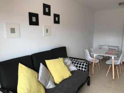 ein Wohnzimmer mit einem schwarzen Sofa und einem Tisch in der Unterkunft Piscina y playa a 2 kilómetros Alojamiento grande para familias in San Juan de Alicante