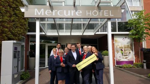 a group of people standing under a merge hotel sign at Mercure Düsseldorf Kaarst in Kaarst