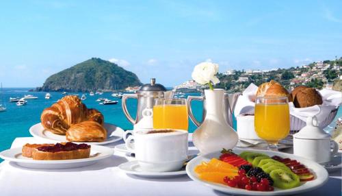a table with breakfast foods and juice and a view of the ocean at Hotel La Gondola in Ischia